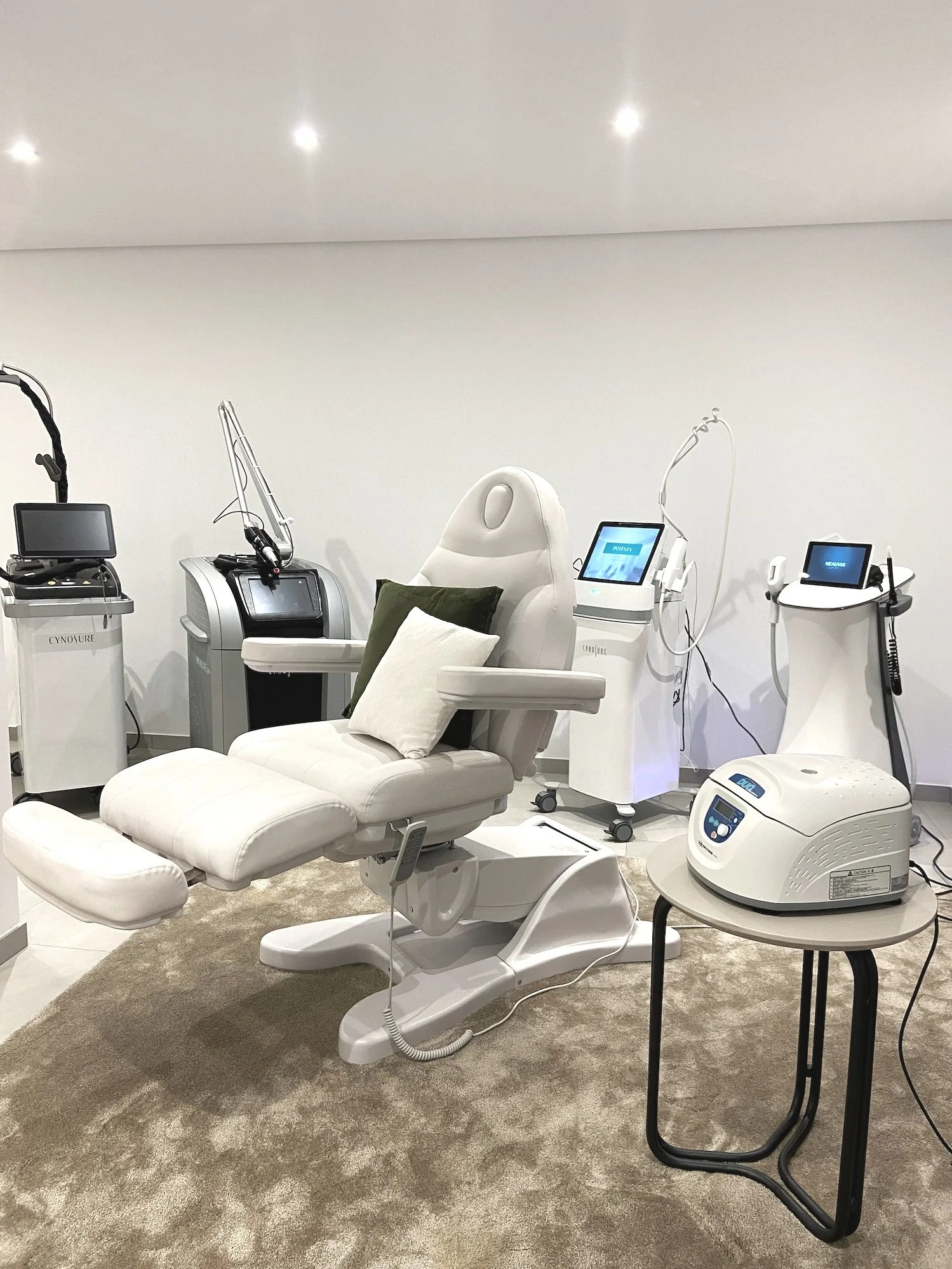 uma cadeira de estética montada no centro da sala, com equipamentos premium de tratamento de pele por trás